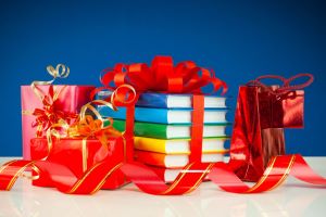 A small pile of gift wrapped packages with ribbons, the central present is not wrapped, but is a stack of colorful books tied with a ribbon