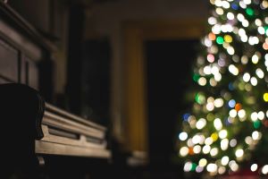 A piano in a room with a Christmas tree, the piano is in focus but the rest of the picture is blurred