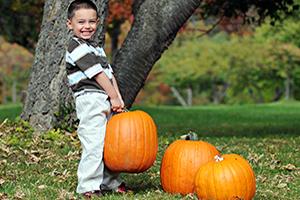 Child playing with a pumpkin in the fall