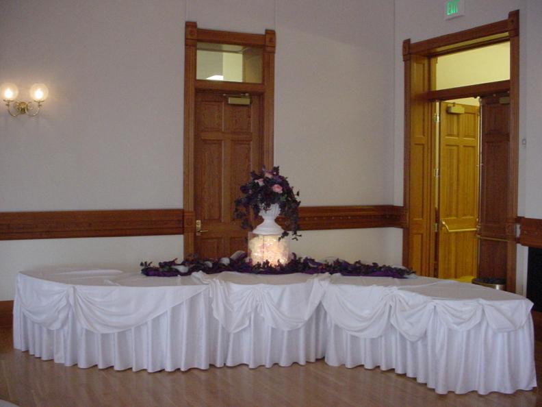 A talbe with an ornate tablecloth and floral arrangement from a past event in the ballroom at the Provo City Library