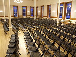 A large ballroom with set up chairs arranged in a theater style